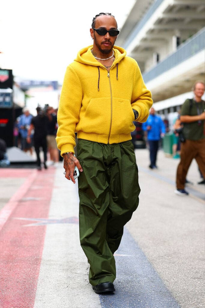  Lewis Hamilton of Great Britain and Scuderia Ferrari arrives in the Paddock during previews ahead of the F1 Grand Prix of United States at Circuit of The Americas, Lewis Hamilton, Louis Vuitton Spring 2026, United States Grand Prix, Austin F1, yellow hoodie, oversized trousers, street style, paddock fashion