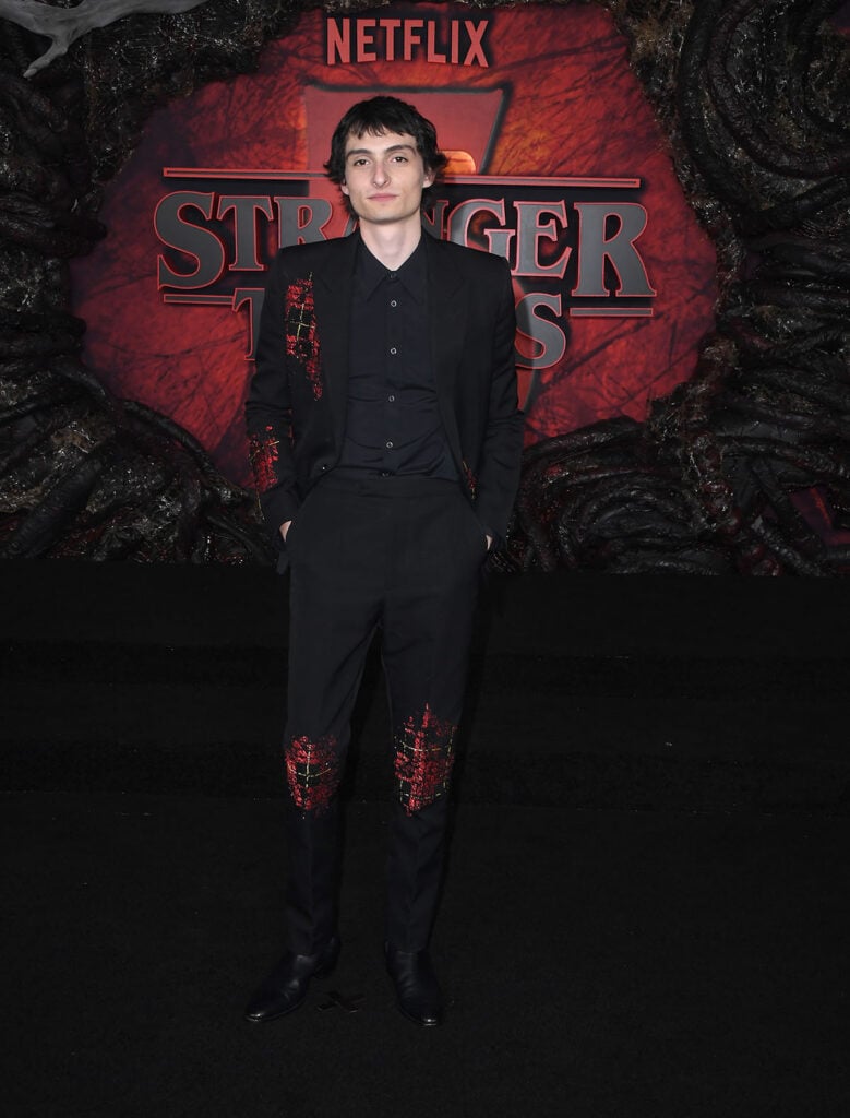 Finn Wolfhard arrives at the Los Angeles Premiere Of Netflix's "Stranger Things" Season 5 , Finn Wolfhard, McQueen Resort 2026 suit, Stranger Things Season 5 LA premiere red carpet, distressed tartan embroidery, youthful gothic edge.