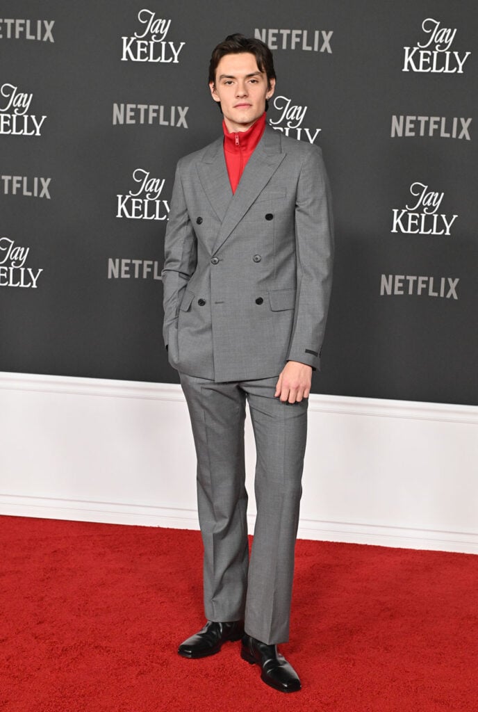Louis Partridge Prada grey suit, Prada menswear red carpet, red zip-up jacket styling, Jay Kelly LA Premiere red carpet, menswear 2025 red carpet