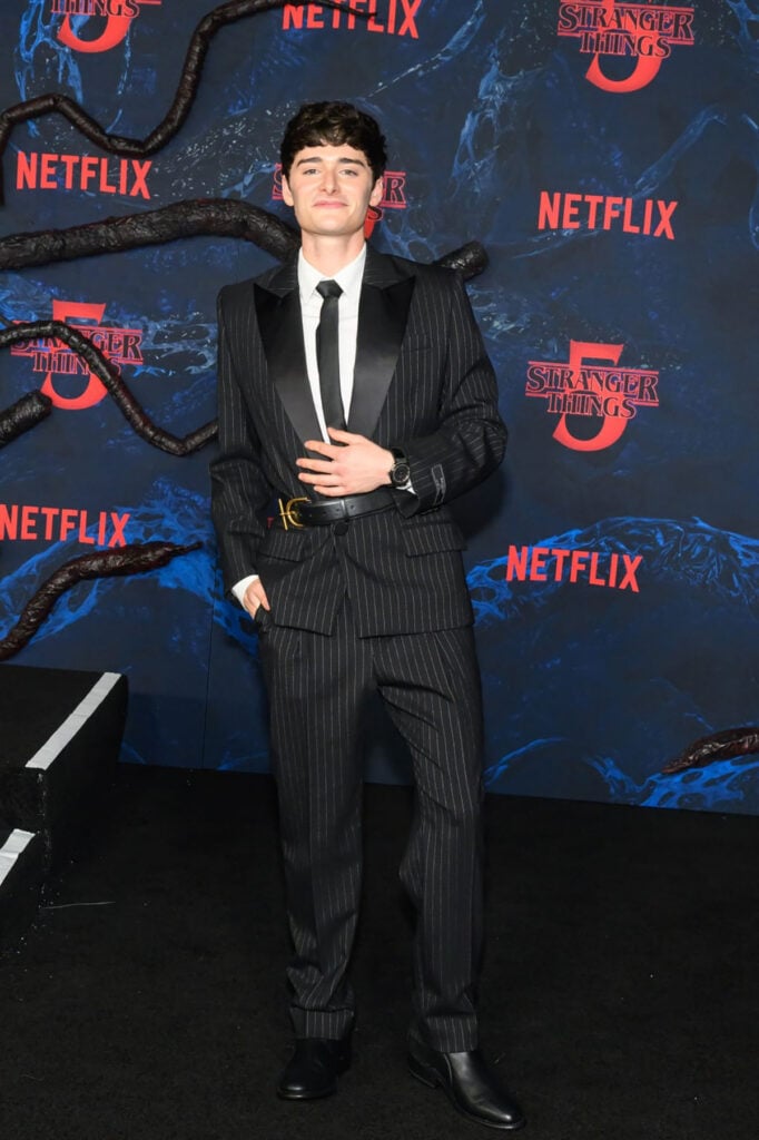 Noah Schnapp, Balmain Fall 2025 pinstripe suit, Stranger Things Season 5 LA premiere red carpet, sharp structured tailoring, Hublot timepiece.