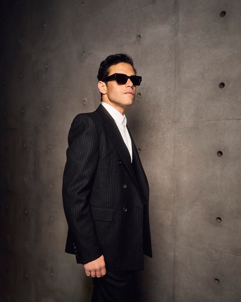 Rami Malek, Saint Laurent front row, Paris Fashion Week, black pinstripe suit, sharp tailoring, actor menswear