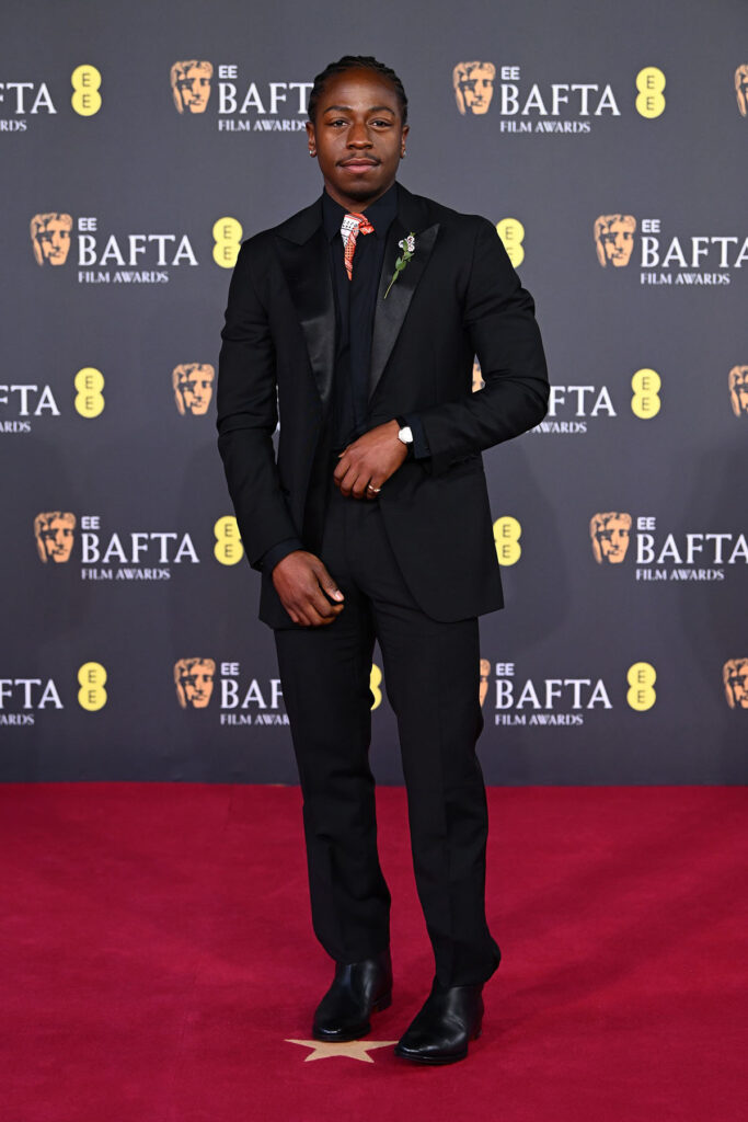 David Jonsson, David Jonsson BAFTAs 2026, BAFTAs menswear, Hermès suit, Hermès scarf tie styling, floral brooch detail, Cartier vintage Vendome timepiece