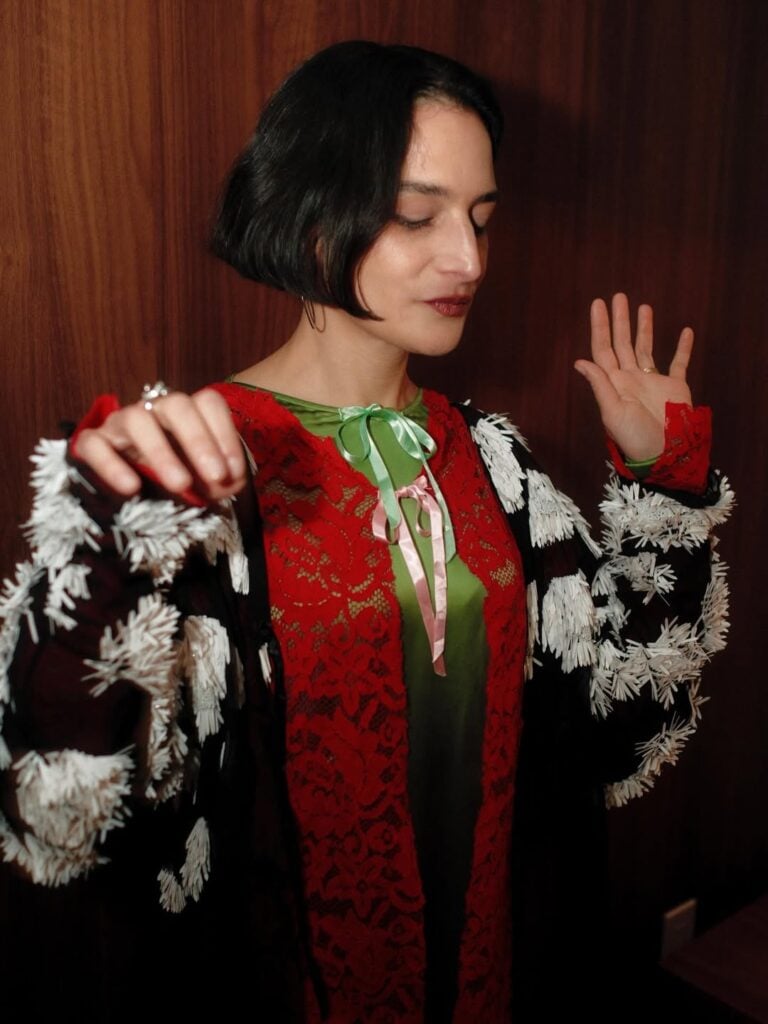 Jenny Slate, Meryll Rogge Spring 2026, Jenny Slate Late Night with Seth Meyers, Meryll Rogge dress, Broadway All Out Jenny Slate, celebrity talk show style, Spring 2026 fashion, red lace mini dress, art school inspired fashion, New York talk show fashion