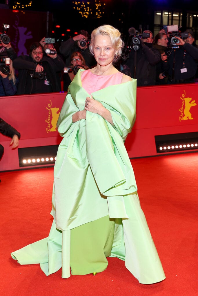 Pamela Anderson Berlin Film Festival 2026, Pamela Anderson Rosebush Pruning premiere, Carolina Herrera Fall 2025 mini cape, Carolina Herrera Resort 2026 gown, Berlin Film Festival red carpet 2026, Pamela Anderson photocall look, Pamela Anderson premiere gown, Carolina Herrera brocade cape, Carolina Herrera Resort 2026 column gown