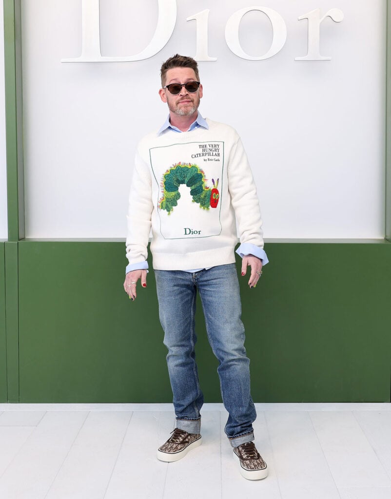 Macaulay Culkin Dior front row, Macaulay Culkin Dior Fall 2026 show, Macaulay Culkin Dior Very Hungry Caterpillar sweater, Macaulay Culkin Dior Paris Fashion Week, Dior Macaulay Culkin fashion week look