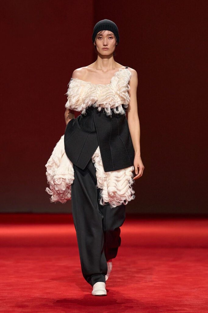 Bottega Veneta Fall 2026 look featuring feathered texture, black tailoring, and carrot-leg trousers on the runway.