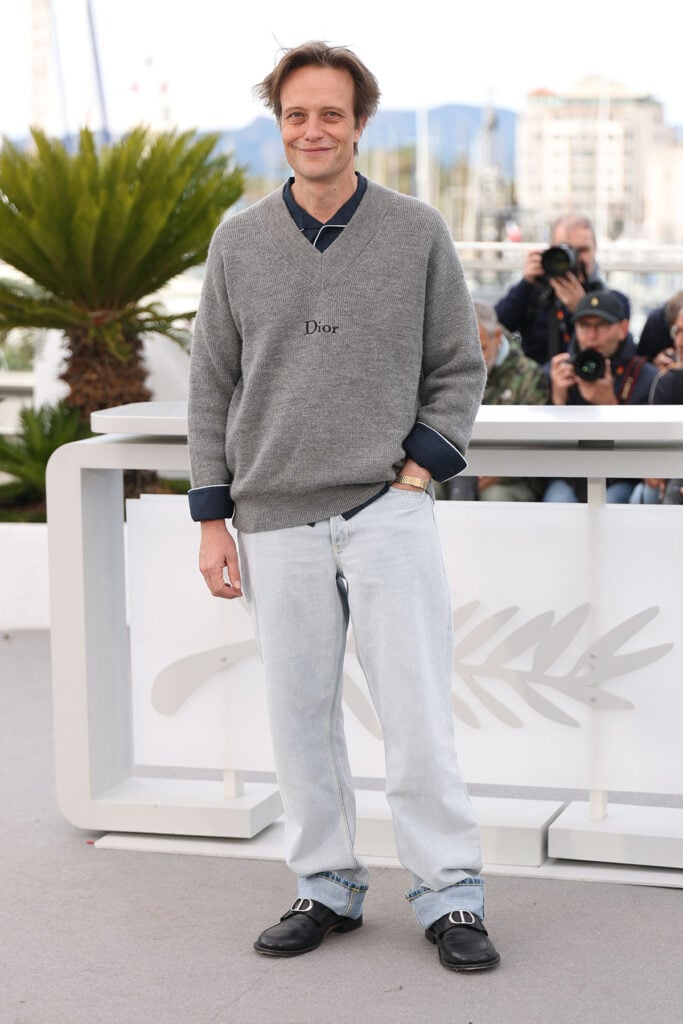 August Diehl wore a grey Dior sweater with relaxed denim to the Fatherland photocall at Cannes Film Festival.