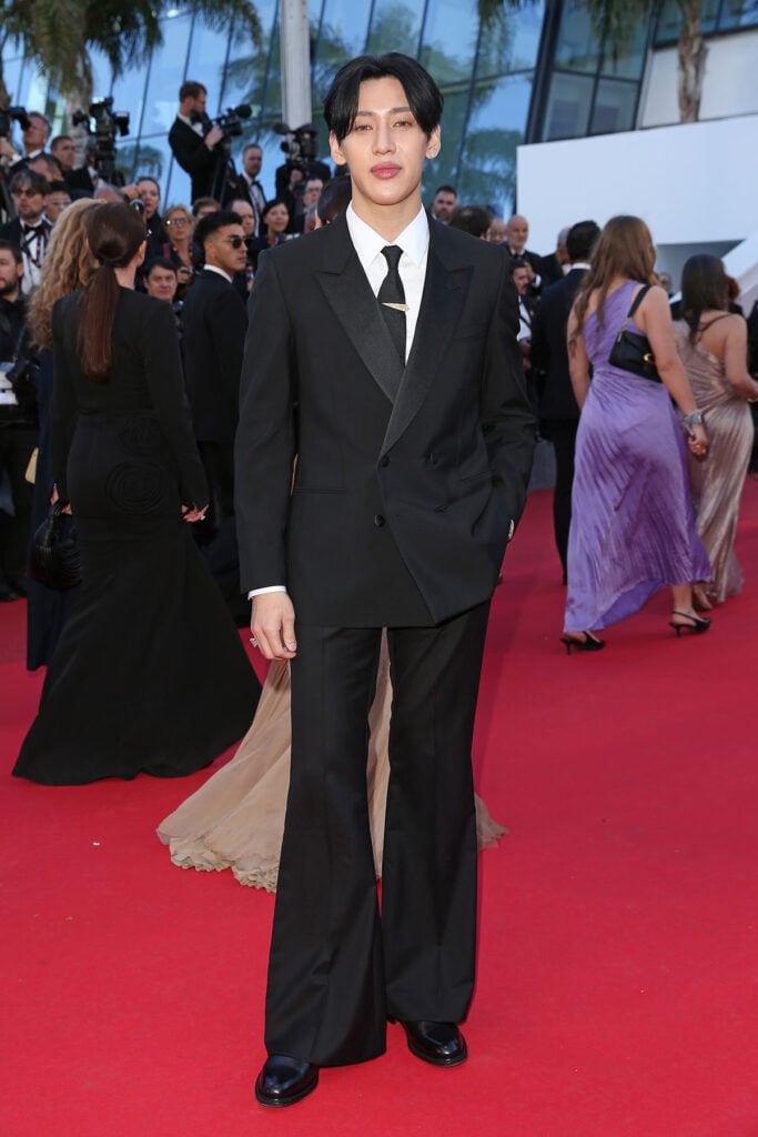 BamBam wore a black Louis Vuitton flared suit with High Jewelry brooches to the Confessions of a Shaman premiere at Cannes Film Festival.