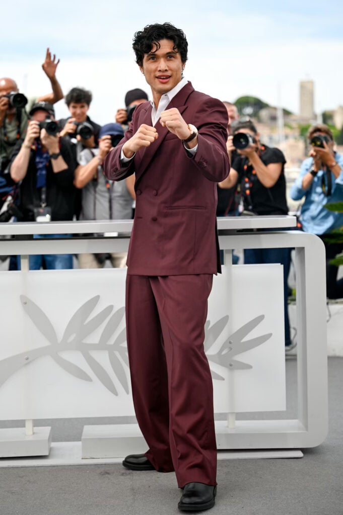 Charles Melton wore a burgundy Louis Vuitton suit with black LV City Chelsea boots to the Cannes Film Festival photocall.
