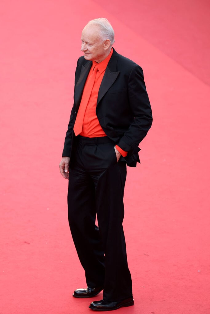 Stellan Skarsgård posed in Loewe tailoring with a vivid red shirt and tie during Cannes Film Festival.