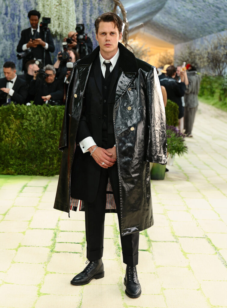 Bill Skarsgård in Thom Browne at the 2026 Met Gala wearing an elongated black patchwork tuxedo with layered textures