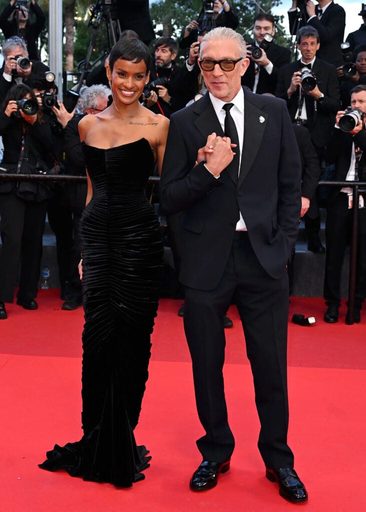Narah Baptista wearing a black Schiaparelli gown with Vincent Cassel in Prada at the Cannes Film Festival