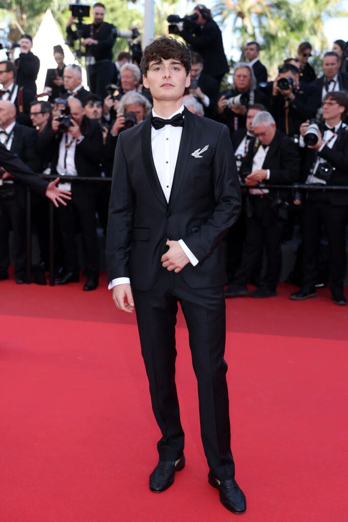 Noah Schnapp wore a black Karl Lagerfeld tuxedo with a Chaumet Magnolia brooch at Cannes Film Festival.