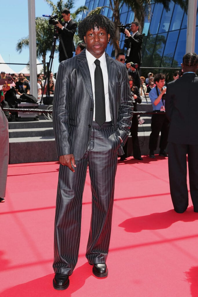 Toheeb Jimoh wore a Hermès Fall 2026 leather pinstripe suit to the Sheep In The Box premiere at Cannes Film Festival.