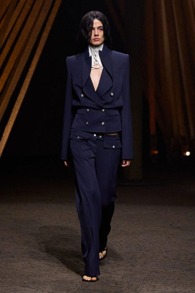 McQueen Spring 2026 navy tailored suit with lace-up corset styling on the runway.