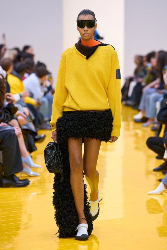 Loewe Fall 2026 runway look featuring a yellow knit and textured black skirt designed by Jack McCollough and Lazaro Hernandez.
