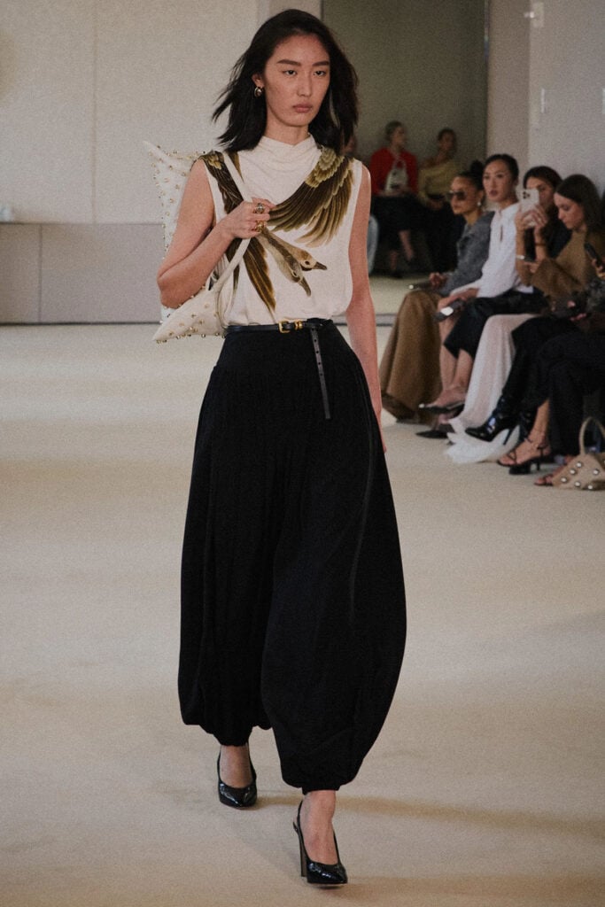 Altuzarra Spring 2026 runway look featuring a bird-print sleeveless top and voluminous black trousers.