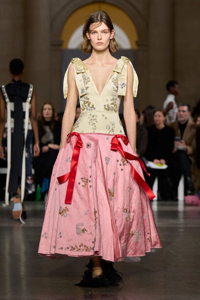 Model walks the Erdem runway wearing the ivory and pink embroidered dress from the Fall 2026 collection.