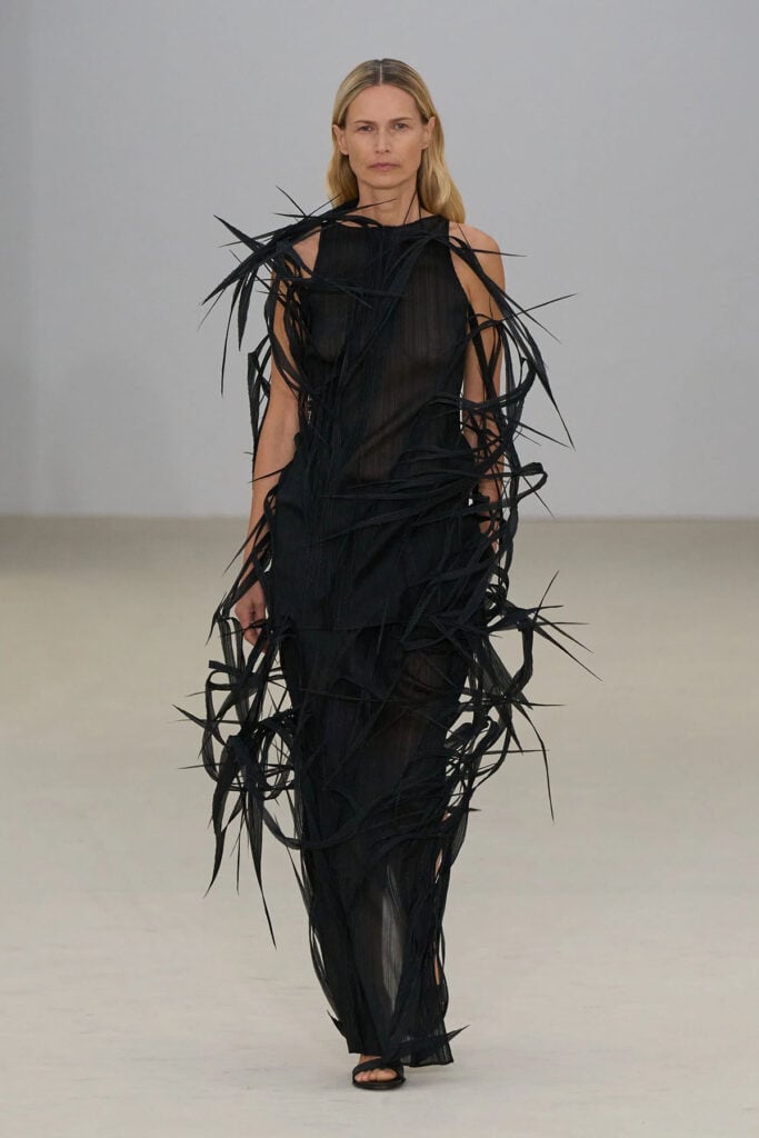 Black Issey Miyake textured dress on the runway featuring sculptural layered detailing and sheer elements