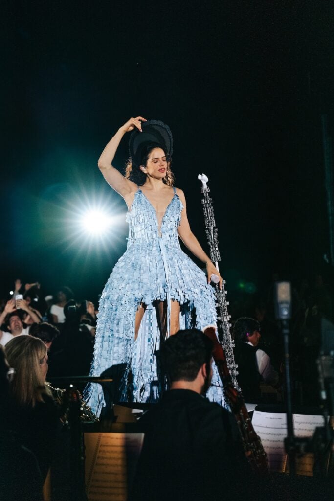 Rosalía performing on the LUX World Tour wearing a custom Dior blue pannier dress inspired by the house's Pre-Fall 2026 collection