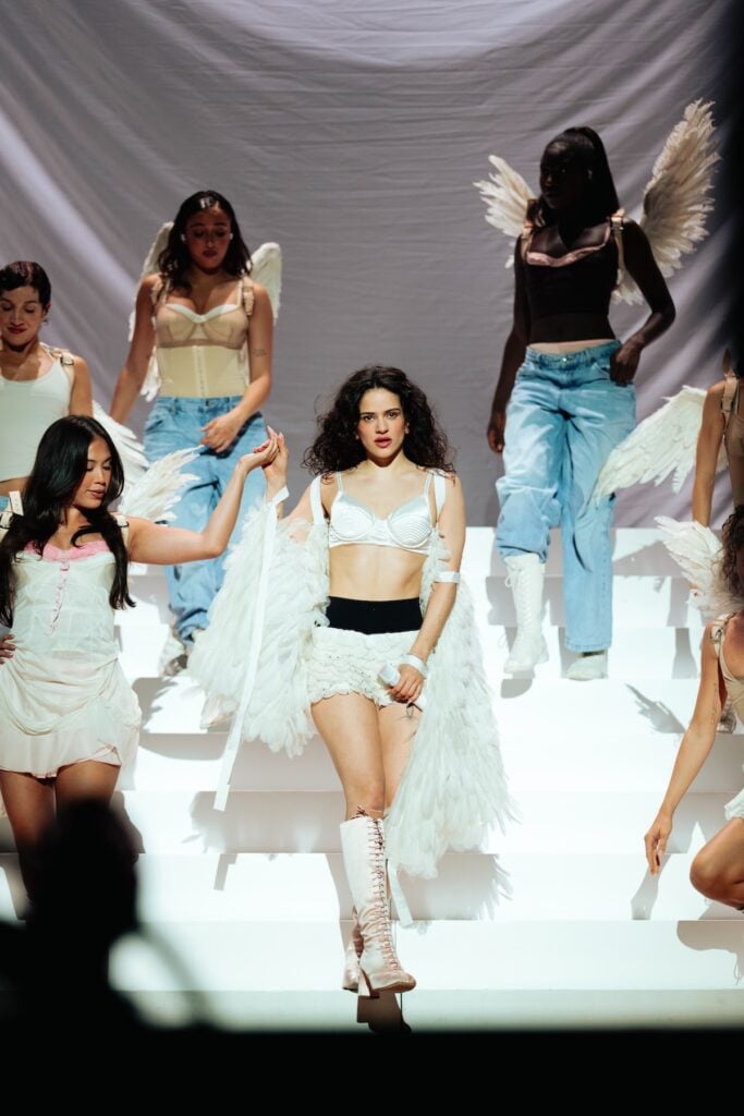 Rosalía performing on the LUX World Tour wearing a custom Dior angel-wing ensemble designed by Jonathan Anderson