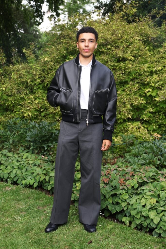 Jay Lycurgo wearing a leather Hermès bomber jacket and grey trousers at the Hermès Maison Bond Street opening in London