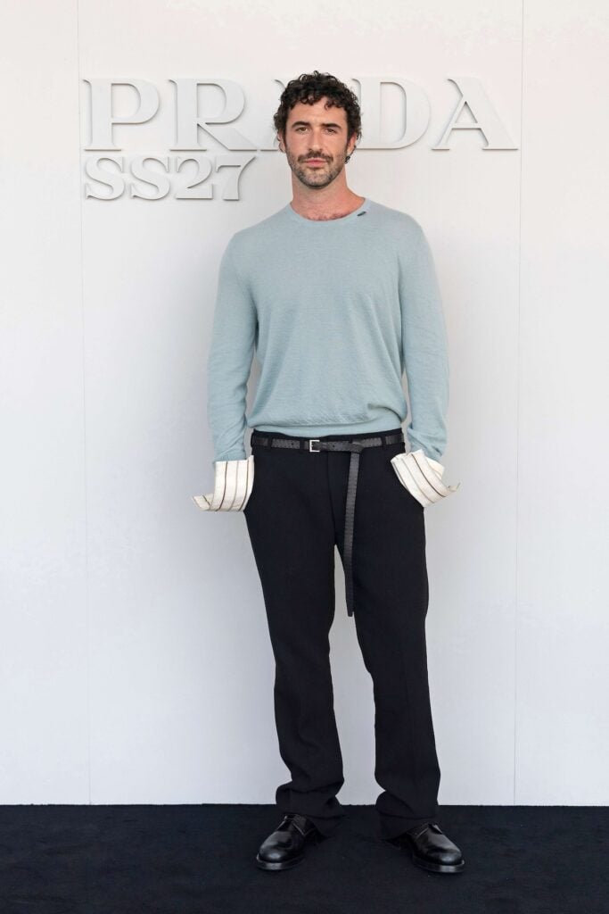 Jordan Firstman attends the Prada Spring/Summer 2027 menswear show in Milan wearing a pale blue Prada knit with oversized cuffs.