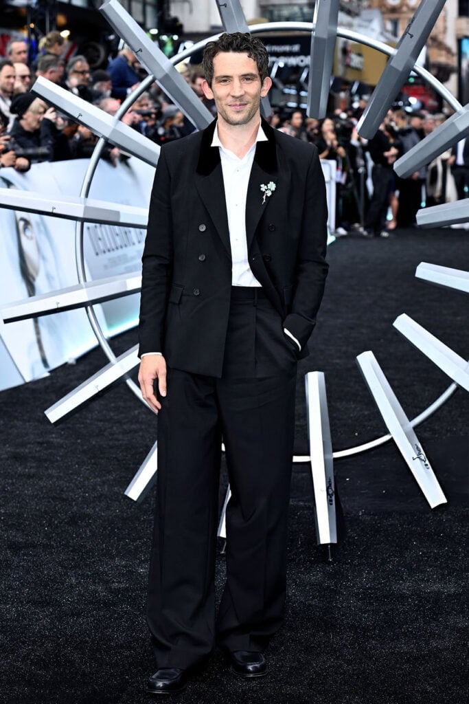 Josh O'Connor wearing a black tailored suit with a shamrock brooch at the Disclosure Day premiere in London.