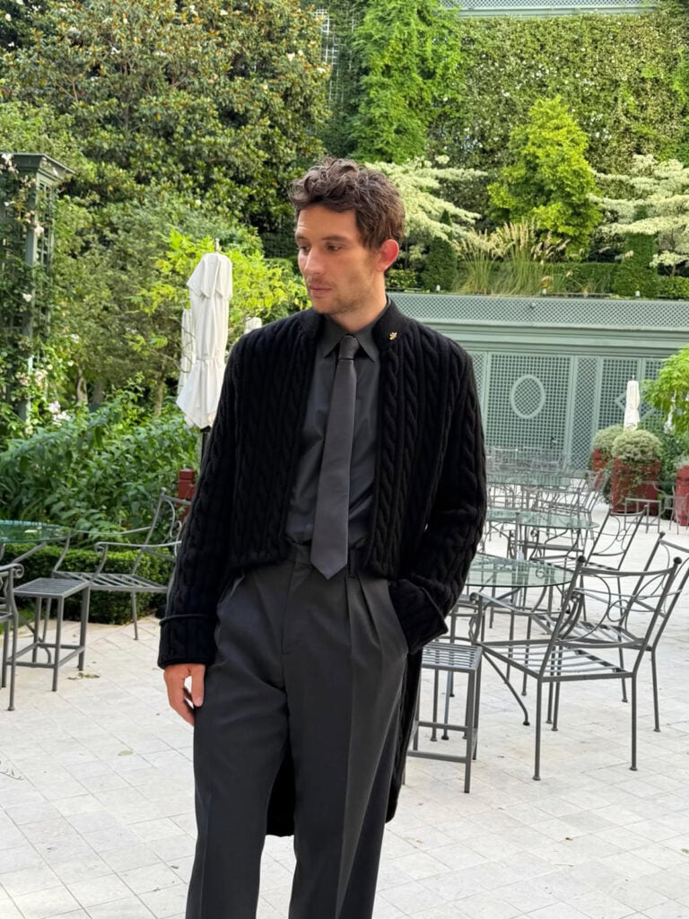 Close-up of Josh O’Connor wearing Dior with a charcoal tie and cable-knit tailoring details in Paris