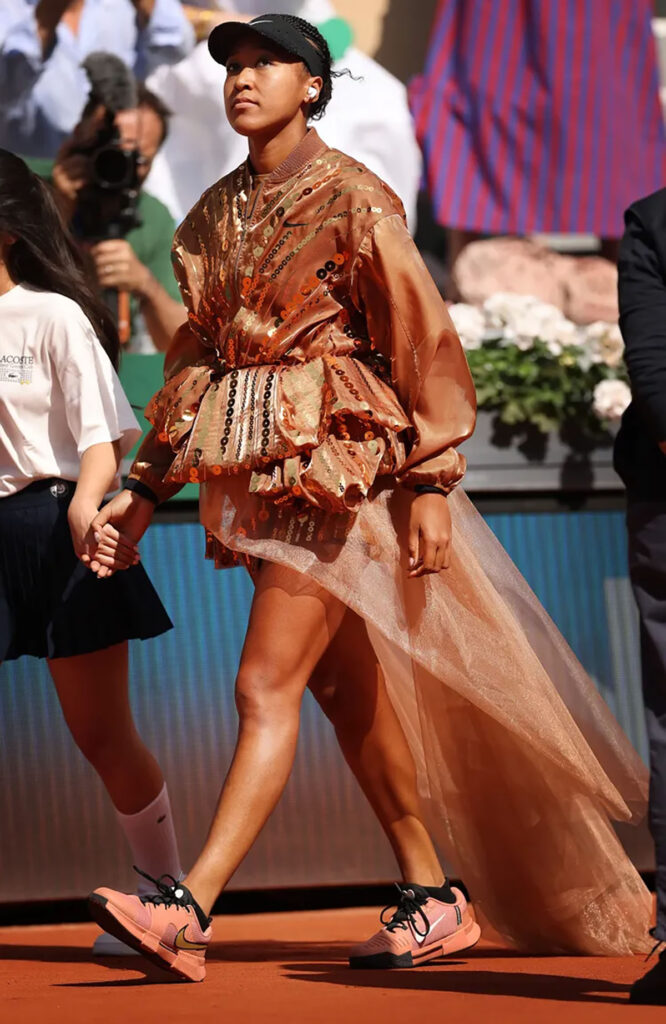 Naomi Osaka arriving courtside in a Nike x Germanier look with flowing white train at Roland-Garros 2026