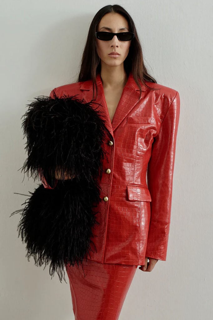 Model wearing The New Arrivals croc-embossed red skirt suit on the runway
