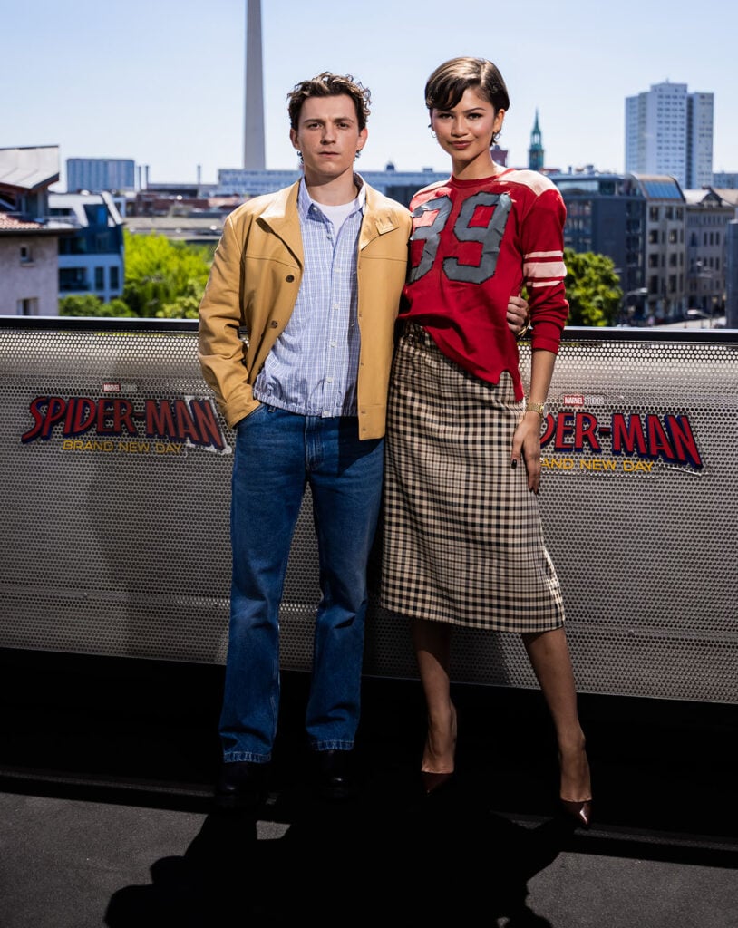 Zendaya wearing a Coach Fall 2026 and Tom Holland in Prada at the Spider-Man: Brand New Day fan event in Berlin.