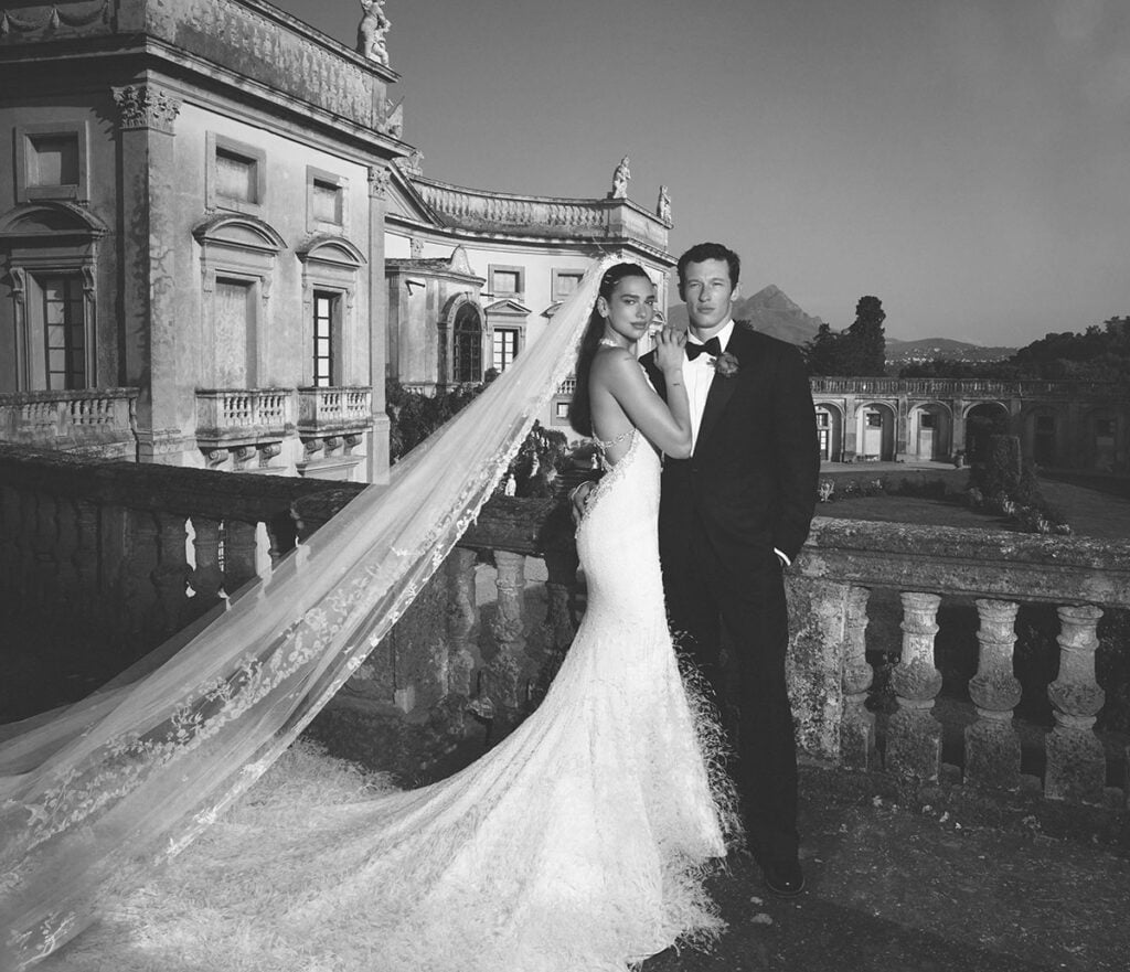 Dua Lipa in a custom Chanel Haute Couture wedding gown with crystal back detailing beside Callum Turner in Sicily.