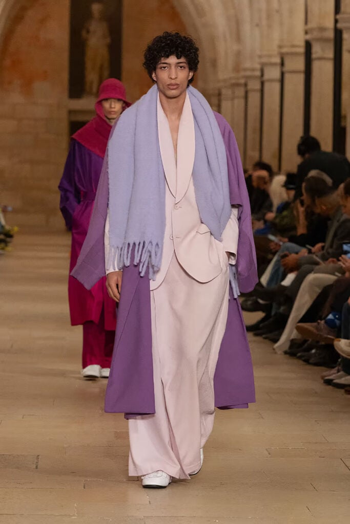 Issey Miyake Fall 2026 runway look featuring soft pink tailoring layered with a violet overcoat