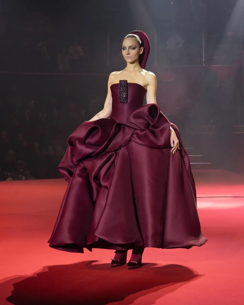 Stéphane Rolland Haute Couture runway look featuring the sculptural burgundy gown and matching headpiece.