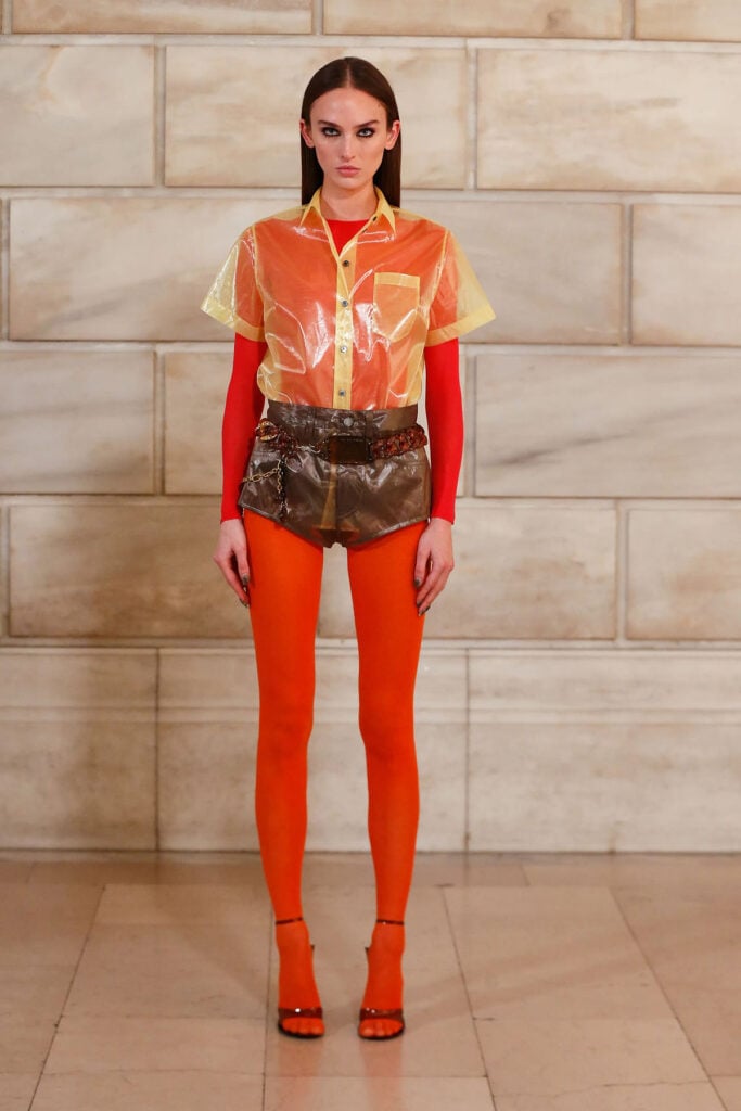 Marc Jacobs Spring 2027 runway look featuring a sheer organza shirt, bodysuit, sheer shorts and vibrant tights.
