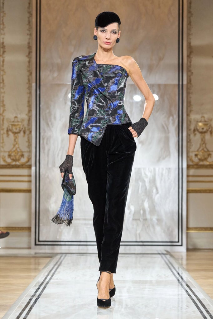 Armani asymmetric one-shoulder jacket paired with slim black velvet trousers on the runway.