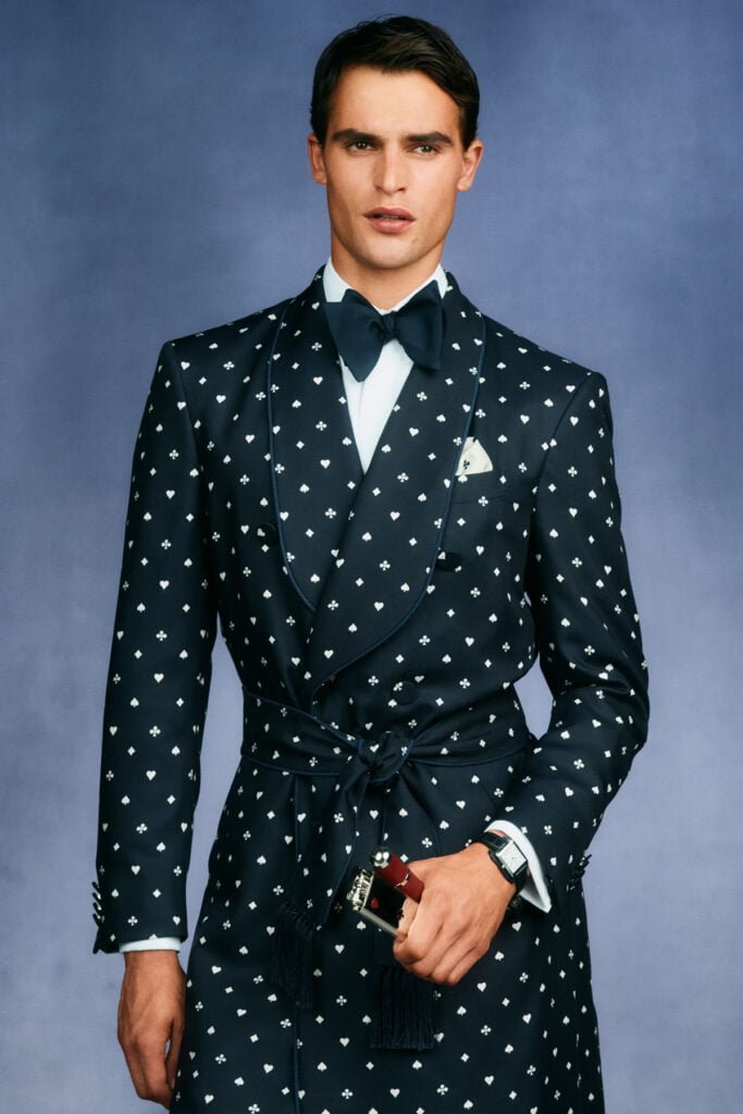 dunhill Spring 2027 menswear shawl-lapel coat with playing-card motif and tasseled waist tie.
