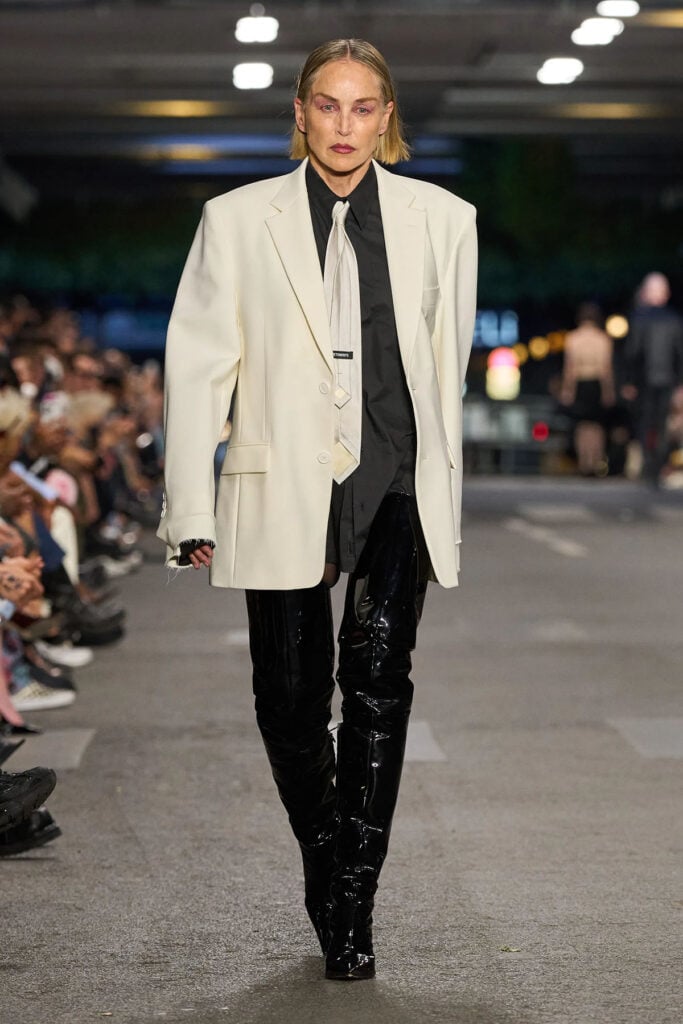 Vetements Fall 2026 runway look featuring the oversized blazer, shirt, tie and patent thigh-high boots.