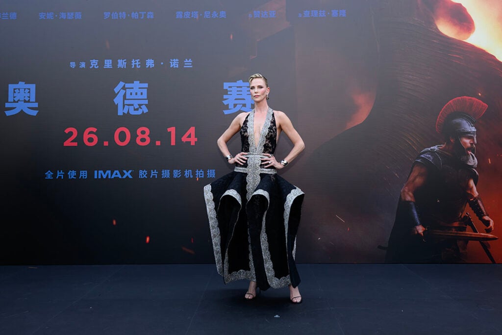 Charlize Theron showcases the sculptural silhouette of her Givenchy lace dress during The Odyssey promotional event in Beijing.