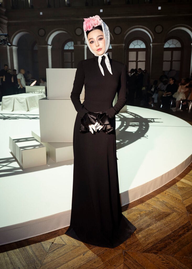 Fan Bingbing attending the Viktor & Rolf Fall 2026 Couture show in a black gown with lace bonnet and pink roses.
