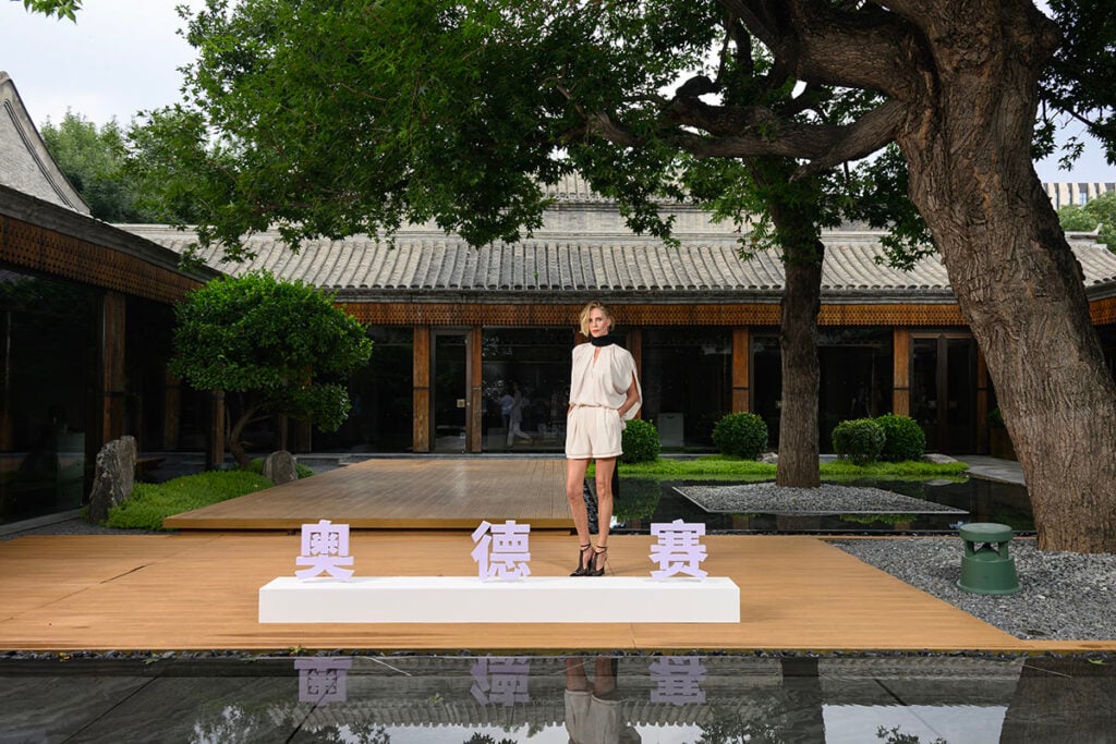 Charlize Theron showcases Lanvin T-bar mesh pumps with her Spring 2026 shorts look at The Odyssey Beijing photocall.