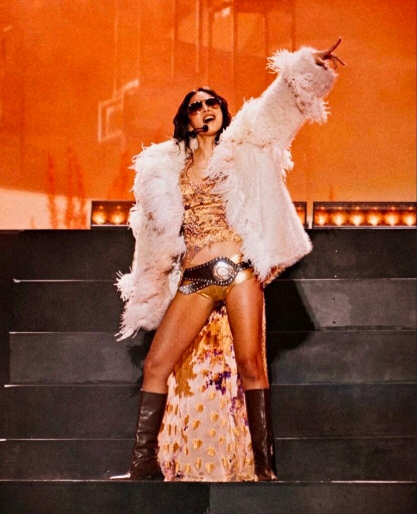 Jennie adds a white Elie Saab Pre-Fall 2025 shearling jacket to her Mad Cool Festival performance look.