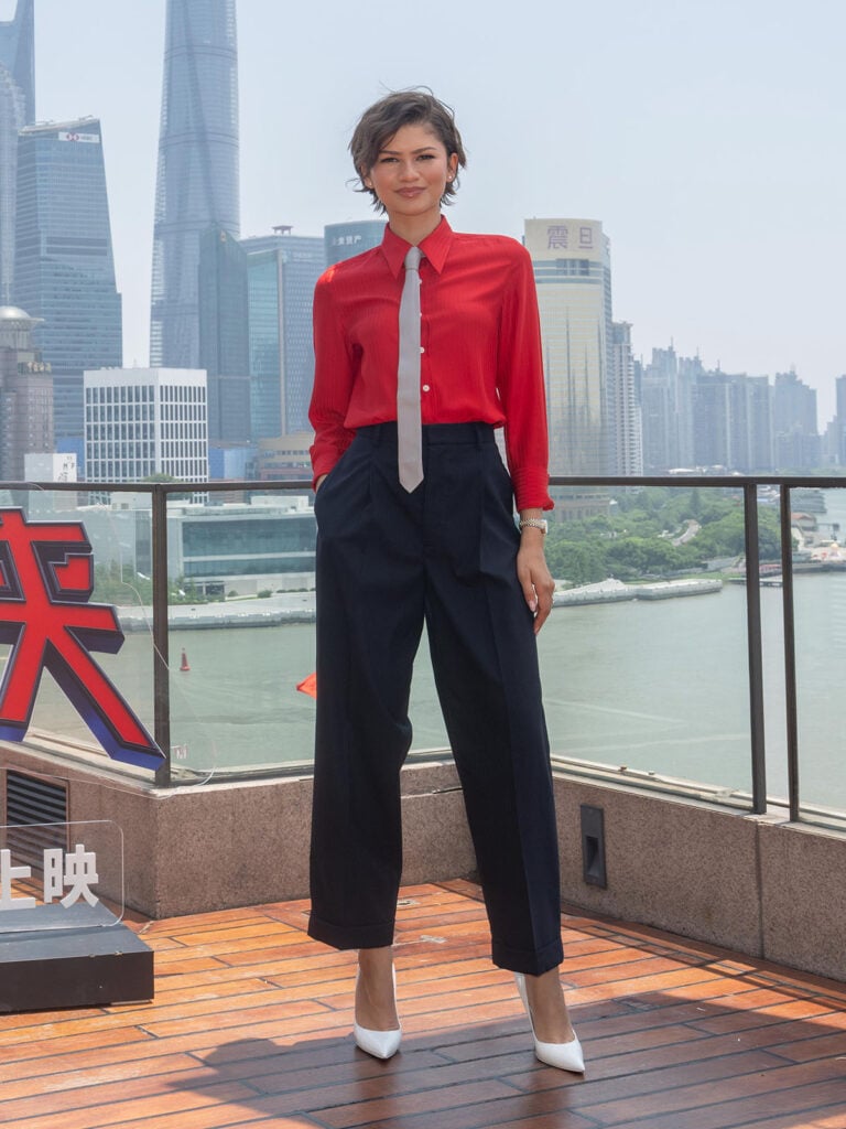 Zendaya wearing Coach Resort 2027 with a red shirt, silver tie and navy trousers at the Spider-Man: Brand New Day Shanghai photocall.
