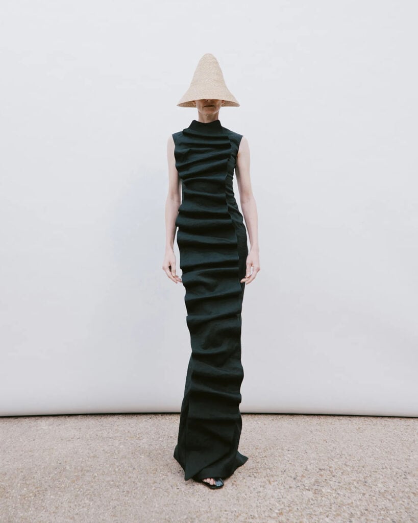 A.W.A.K.E. Mode Spring 2026 black column dress featuring asymmetric horizontal ruffles on the runway.