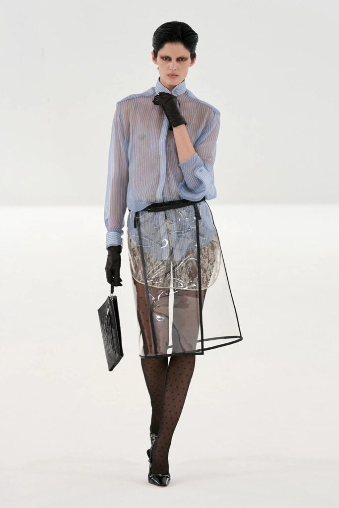 Tom Ford Fall 2026 look featuring a striped shirt, PVC wrap skirt, lace shorts and polka-dot tights on the runway.