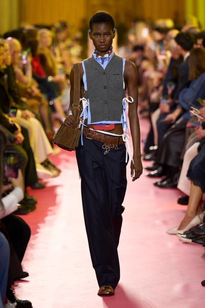 Miu Miu Spring 2026 runway look featuring the sculpted shirt and knit vest worn by Bella Ramsey.