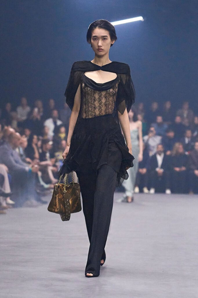 Valentino Spring 2026 runway look featuring the lace bodice, draped peplum and navy trousers.