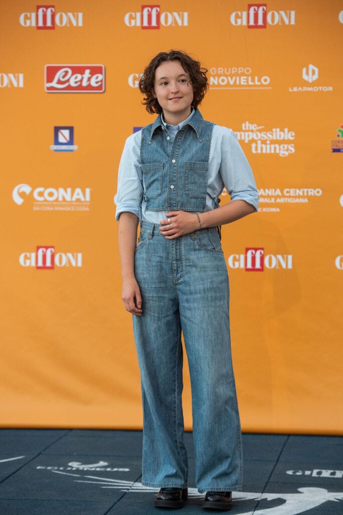 Bella Ramsey wearing a Miu Miu denim vest and wide-leg jeans to the 'Sunny Dancer' premiere at the Giffoni Film Festival.