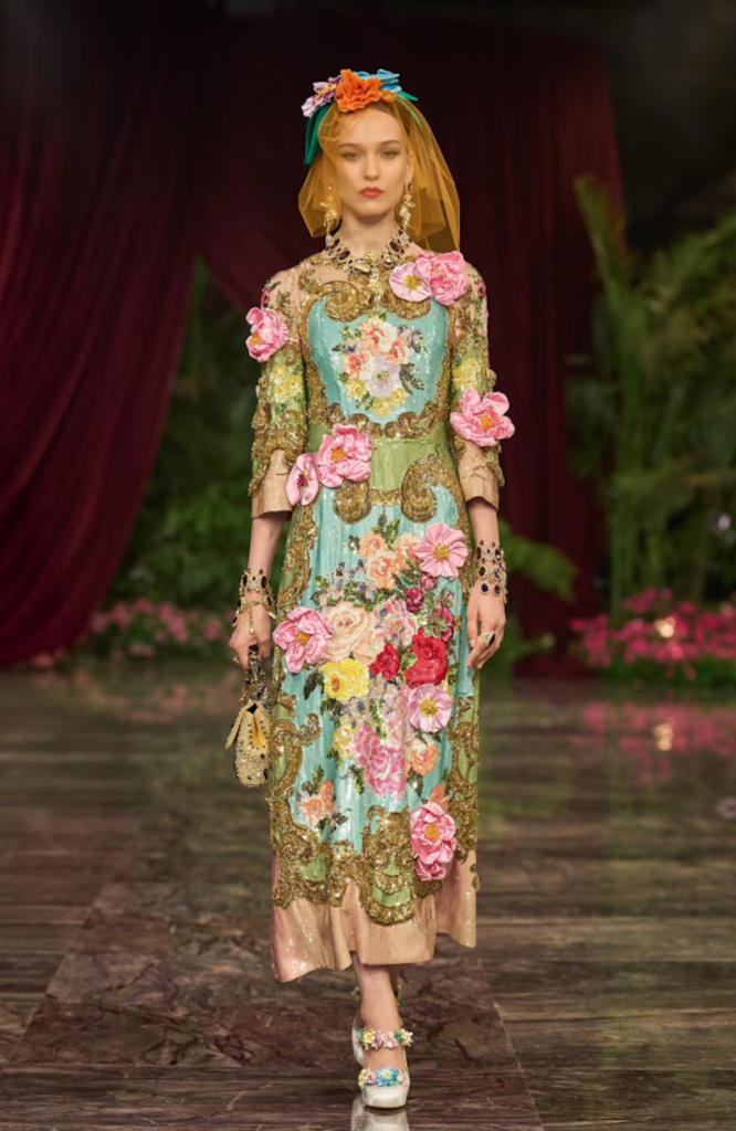 Dolce & Gabbana Alta Moda Taormina 2026 Bartolomea look featuring an embellished organza dress and floral headpiece.